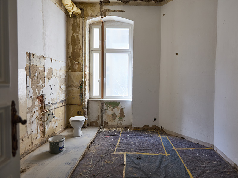 Renovierungsbedürftiges Badezimmer mit freigelegten Wänden und abblätternder Farbe vor einer umfassenden Badsanierung in Wiesbaden.