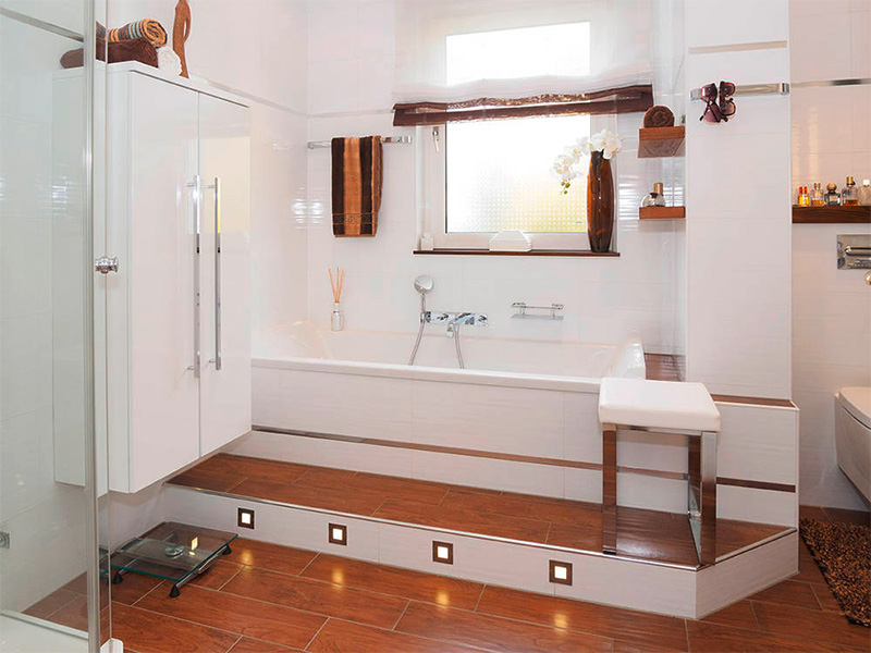 Modernes Badezimmer mit Badewanne, Glasdusche, weißen Wandfliesen, braunen Bodenfliesen und stilvoller Beleuchtung nach einem Badumbau in Wiesbaden.