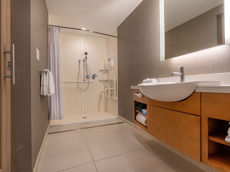 Moderne bodengleiche Dusche mit rutschfestem Fliesenboden, Haltegriffen und großzügigem Einstieg für mehr Komfort und Barrierefreiheit.