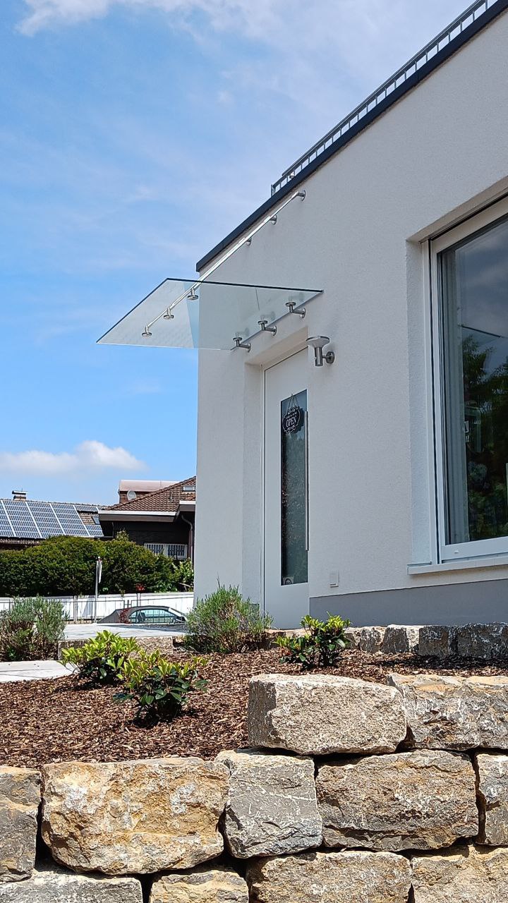 Weiße Haustür mit Glas-Einsatz und Überdachung aus Sicherheitsglas, modernes Design von Bauelemente Orth in Wiesbaden.