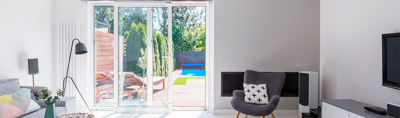Helles Wohnzimmer mit modernem Sessel, dekorativem Kissen sowie großen Fenstern und Türen in Wiesbaden für stilvolles Wohnen.