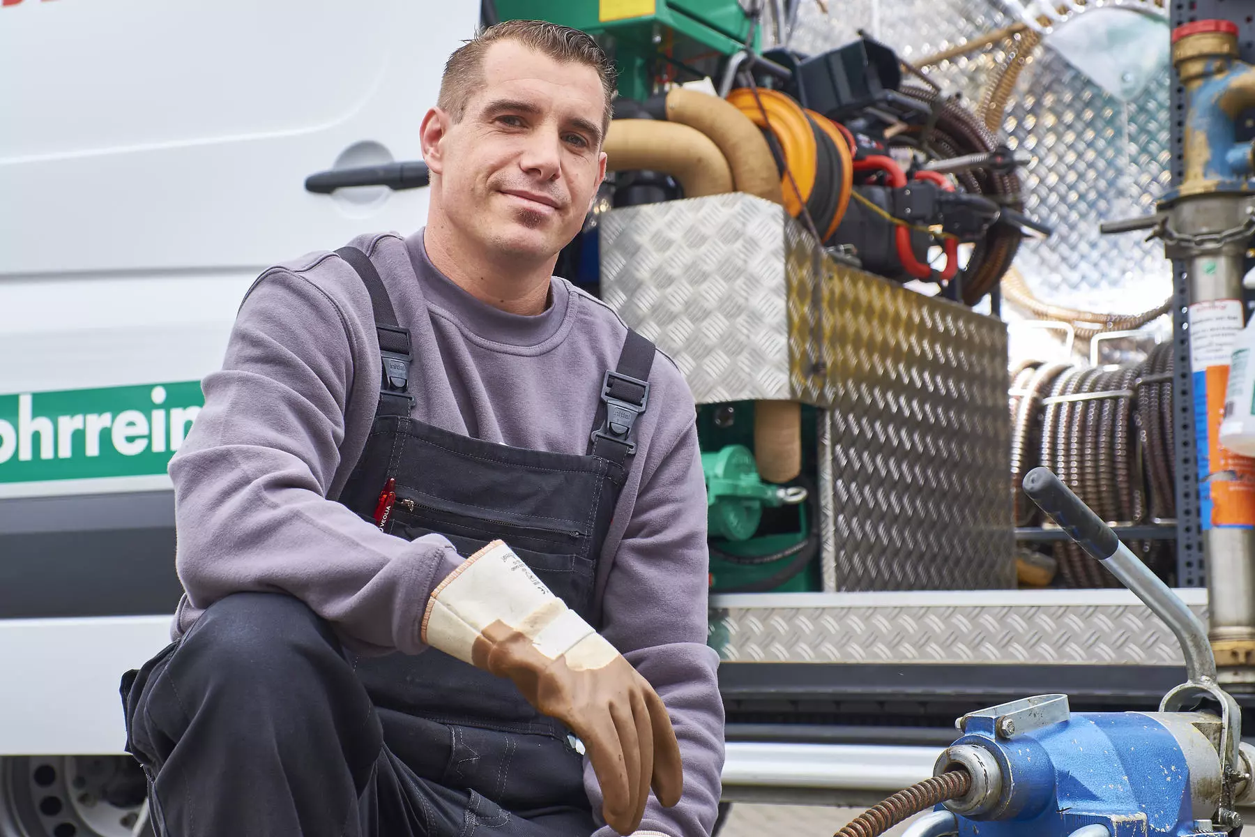 Fachkraft bei Kanal  und Abwasserarbeiten an Rohrleitung mit schwerem Gerät, symbolisiert professionelle Kanalreinigung und technische Wartung städtischer Abwassersysteme.