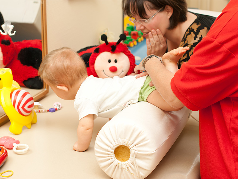 Frühförderung für Babys in Wiesbaden: Therapeutische Übung mit einer Krabbelrolle zur Unterstützung früher Bewegungsentwicklung.