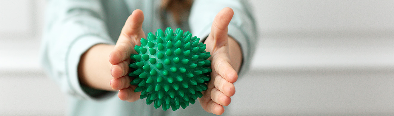 Physiotherapie für Kinder in Wiesbaden: Handtherapeutische Übung mit Massageball zur Förderung der taktilen Wahrnehmung und Handmotorik.