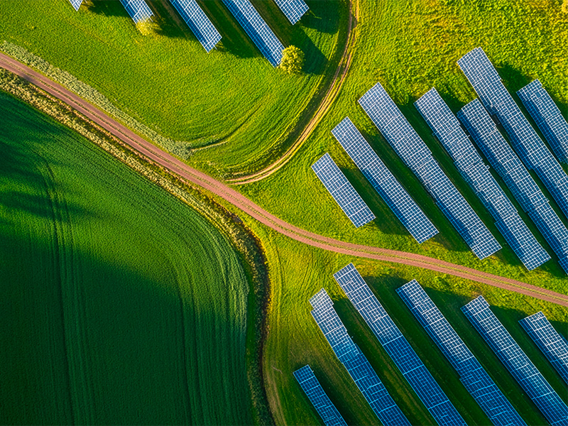 Luftaufnahme eines großen Solarparks zwischen grünen Feldern zur nachhaltigen Stromerzeugung durch Photovoltaik in Wiesbaden.
